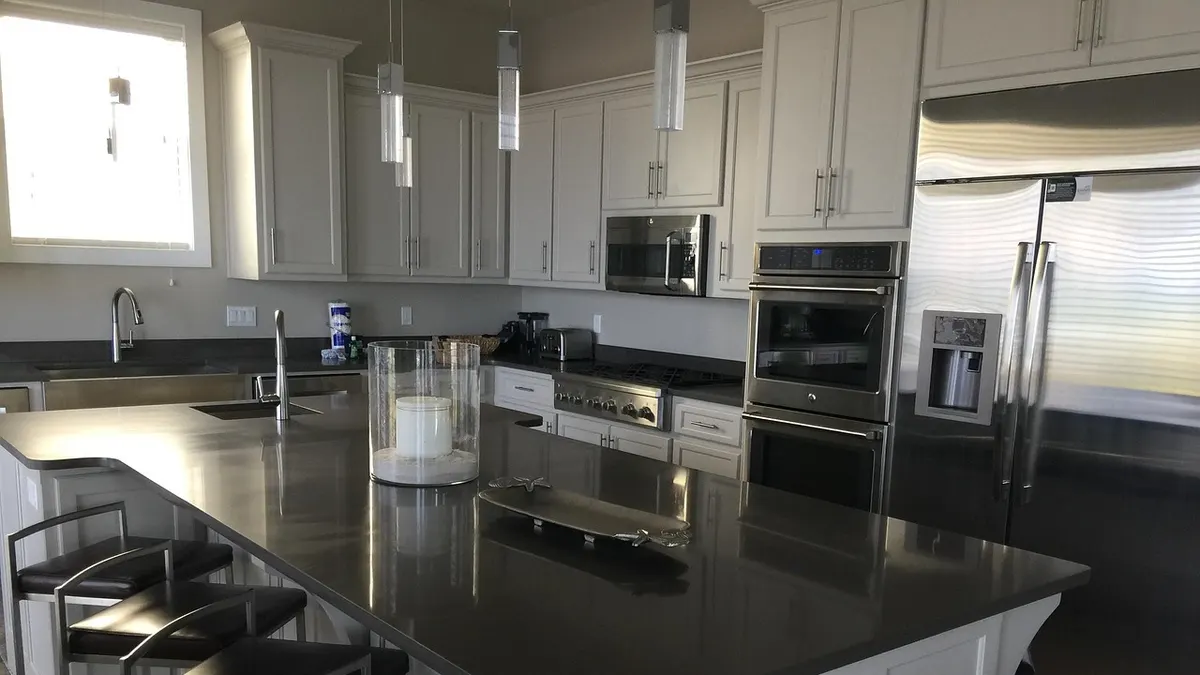 Cozinha moderna com ilha escura e geladeira inox