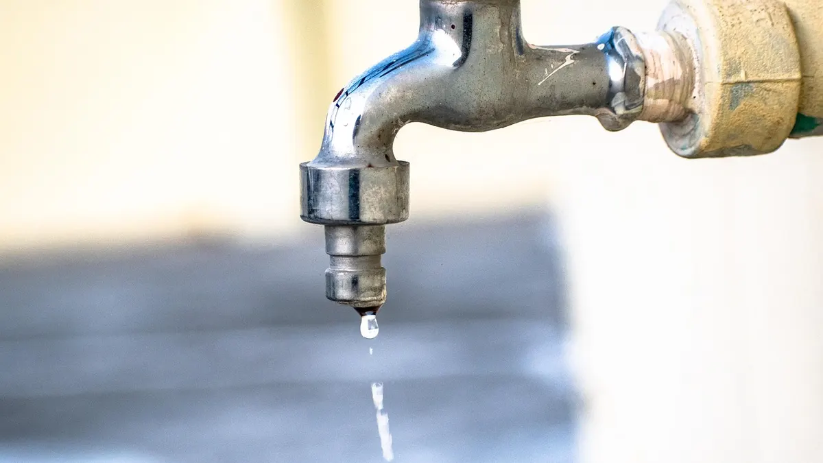 Torneira metálica com gota de água caindo
